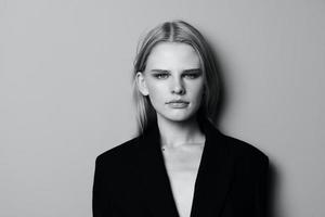 närbild porträtt av fundersam allvarlig blond modell i svart jacka Framställ lutande på de studio vägg. eleganta minimalistisk skjuta foto