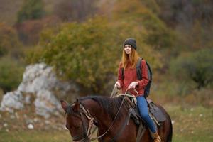 kvinna vandrare ridning en häst på natur resa foto