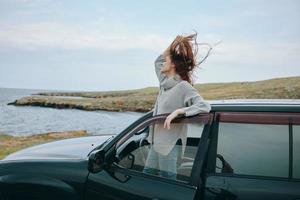 kvinna med röd hår i en Tröja nära de bil natur kvinna avkopplande foto