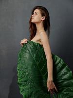 modell innehav en stor blad över henne kropp foto