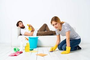 de man lögner på de soffa kvinna tvättar de golv tillhandahålla tjänster interiör hushållsarbete foto