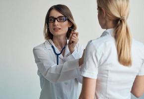 de läkare lyssnar till de patientens hjärtslag genom en stetoskop på en ljus bakgrund beskurna se foto