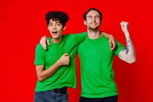 två glad vänner kram grön t-tröjor känslor kommunikation röd bakgrund foto