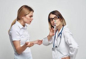 en sjuksköterska i en medicinsk klänning innehar en spruta i henne hand och en patient på en ljus bakgrund foto