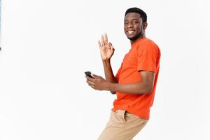 emotionell man afrikansk mobil telefon gestikulerar med hans händer och orange t-shirt foto