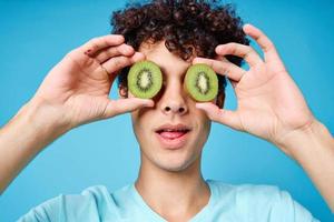 lockigt kille med kiwi i hans händer närbild färsk frukt foto