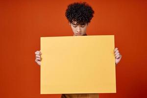 kille med lockigt hår gul affisch reklam röd isolerat bakgrund foto