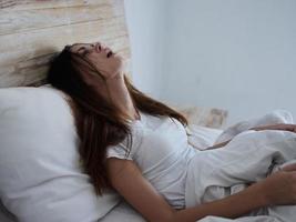 sjuk kvinna med öppen mun lögner i säng temperatur känsla sjuk foto