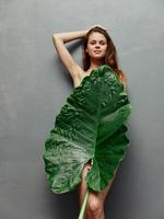 kvinna med naken kropp dölja Bakom stor grön blad foto