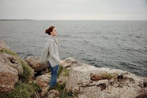 skön kvinna frihet promenad på de sten kust avslappning begrepp foto