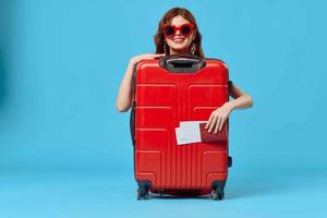 kvinna med röd resväska Sammanträde på de golv pass och plan biljetter livsstil foto