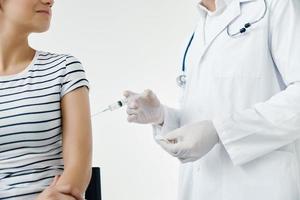 en läkare i en vit täcka gör ett injektion i de axel av en kvinna patient vaccination foto