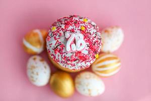 påsk kakor - traditionell Kulich och gyllene ägg på en rosa bakgrund. paska påsk bröd i ryska brev xb foto