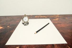vit papper, en klocka och en penna foto