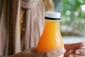 kvinnor innehav en plast flaska av orange juice foto