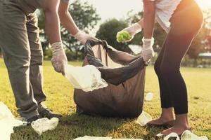 ung människor plockning upp sopor plast för rengöring på parkera foto