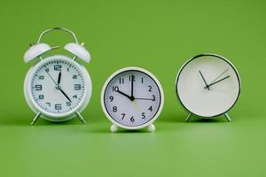 vit klocka på grön bakgrund begrepp av tid tid är Viktig till arbete foto