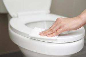 kvinna använder sig av vävnad papper rena de toalett i de badrum på Hem. foto