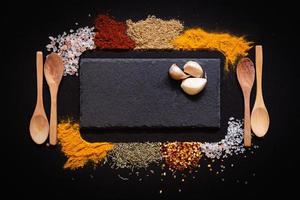 uppsättning av olika kryddor på svart sten tabell. topp se med kopia Plats. foto