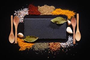 uppsättning av olika kryddor på svart sten tabell. topp se med kopia Plats. foto
