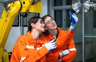 i ett elektronisk delar anläggningen, två kvinna ingenjörer i de växt, inspekterande och testning robot händer Begagnade i de produktion av elektronisk komponenter. foto