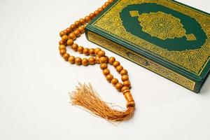 de helig al quran med skriven arabicum kalligrafi menande av al quran och radband pärlor eller tasbih på vit bakgrund, isolerat med kopia Plats. foto