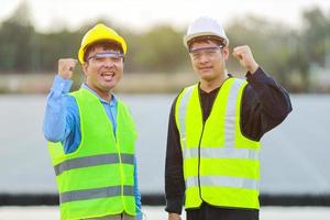 två professionell ingenjörer diskuterar och glad i Framgång under arbetssätt på de paneler på sol- energi på boj flytande.eco teknologi för elektrisk kraft i industri. foto