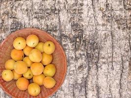 aprikoser i en flätad skål på en träbordbakgrund