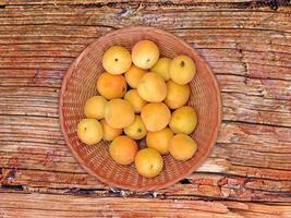 aprikoser i en flätad skål på en träbordbakgrund