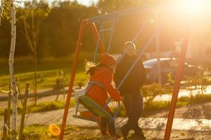 Lycklig liten flick på gunga i parkera foto