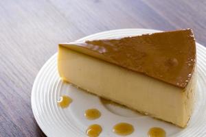 hemlagad karamell vaniljsås pudding på en vit platta på ett träbord
