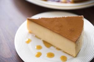 hemlagad karamell vaniljsås pudding på en vit platta på ett träbord foto