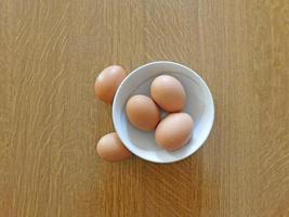 bruna ägg i en vit skål på ett träbord bakgrund