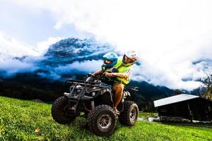 Lycklig familj ridning och ser quad cykel på berg. söt pojke på fyrhjuling. familj sommar semester aktivitet. foto