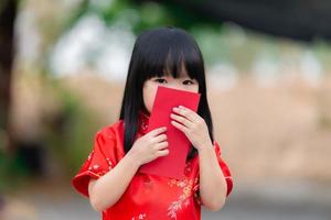 porträtt skön asiatisk liten flicka i Cheongsam klänning, thailand människor, glada kinesisk ny år koncept, glad liten asiatisk flicka i kinesisk traditionell klänning foto