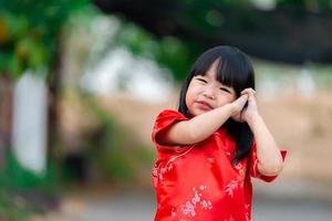 porträtt skön asiatisk liten flicka i Cheongsam klänning, thailand människor, glada kinesisk ny år koncept, glad liten asiatisk flicka i kinesisk traditionell klänning foto