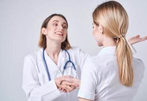 Lycklig kvinna läkare i medicinsk klänning med stetoskop och patient tillbaka se foto