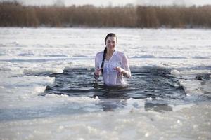 belarus, de stad av gomel, januari 19, 2017. fest av de dop av Jesus. ortodox rit badning i de is hål. en kvinna badar i is vatten. foto