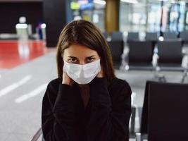 kvinna i medicinsk mask ser ett huvud flygplats väntar stänga upp foto