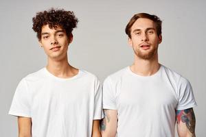 två vänner i vit t-tröjor roligt känslor isolerat bakgrund foto