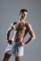 stark manlig idrottare med böjd ärm muskler på grå bakgrund foto