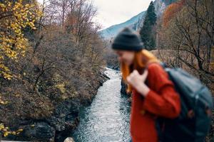 glad kvinna vandrare på de bro nära de flod bergen resa natur foto