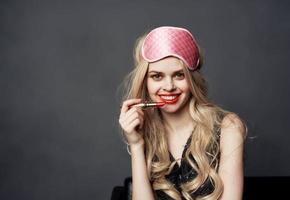 full blond med ljus smink på henne ansikte röd mun och en rosa sömn mask foto