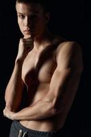 porträtt av sexig kroppsbyggare med naken torso ärm muskler kondition svart bakgrund foto