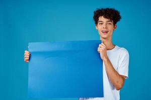 glad kille med lockigt hår och blå attrapp affisch reklam foto