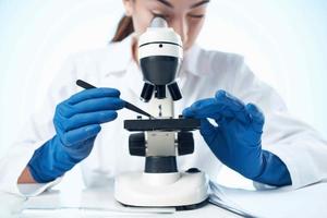 kvinna laboratorium assistent ser genom en mikroskop forskning vetenskap teknologi foto