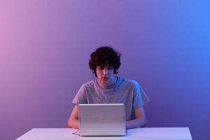 kille i hörlurar i främre av bärbar dator underhållning violett bakgrund foto
