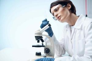 kvinna vit täcka laboratorium mikroskop professionell testning foto