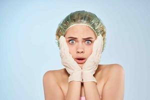 kvinna med bar axlar innehav henne ansikte i handskar hud vård dermatologi foto