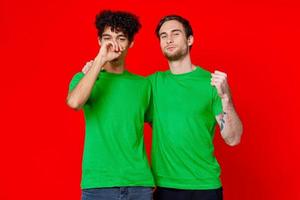 rolig vänner grön t-tröjor kramar känslor glädje röd bakgrund foto